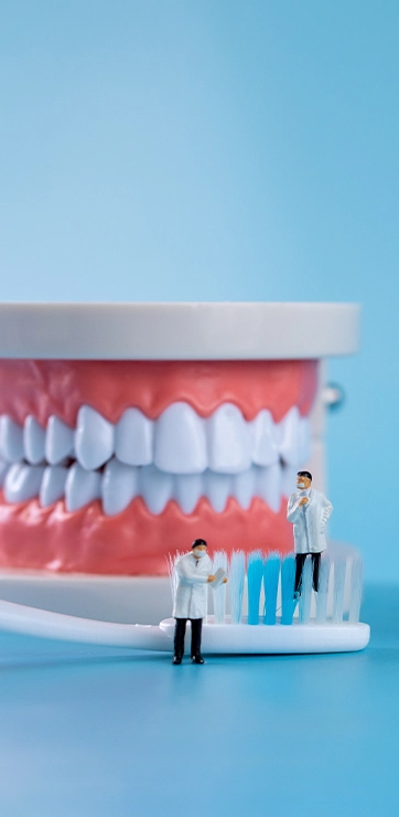 Tiny Dentists On Toothbrush With Blurred Blue Background